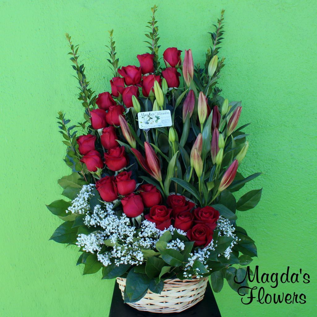 Moonlit lilies - Capture the beauty of the night sky with this mesmerizing floral basket. It features a thick cresent-moon shaped arrangement of red roses, surrounded by white and red lilies, lush greenery and all nestled in a wicker basket. This unique and elegant basket is perfect for any occasion, from a romantic gesture to a special celebration.