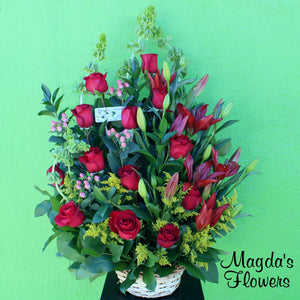 Vibrant Blossom - This floral basket is an eye-catching and elegant arrangement of vibrant red roses, graceful lilies, pretty pink corralberry, and delicate shellflower. The wicker basket adds a rustic charm to the bouquet, making it perfect for a variety of occasions. Whether you're looking to surprise someone special or simply want to add a touch of beauty to your home, this vibrant basket of flowers is sure to delight.