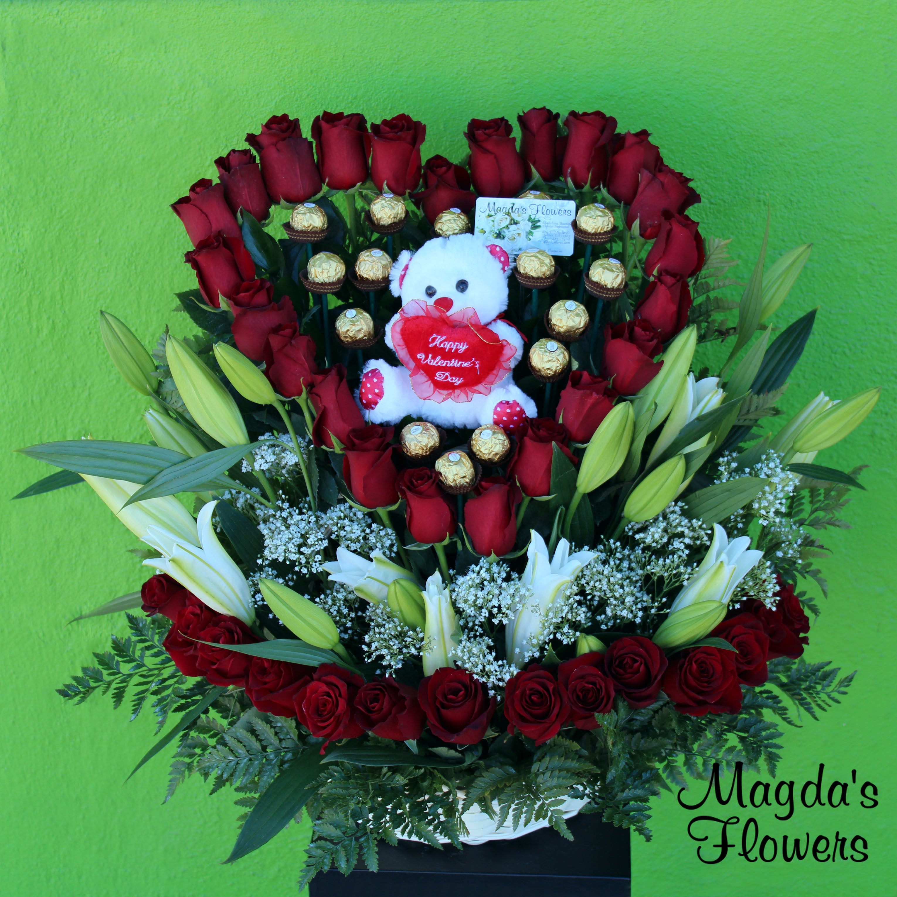 Amor Eterno - This romantic floral arrangement is the perfect symbol of your never-ending love. It features a lovely heart-shaped arrangement of deep red roses, chocolates and a teddy, nestled on a bed of white lilies, red roses and lush greenery. The combination of these flowers creates a stunning bouquet that will remind your loved one of your eternal love. Perfect for Valentine's Day, Anniversaries, or any special occasion that calls for a heartfelt gesture of eternal love.