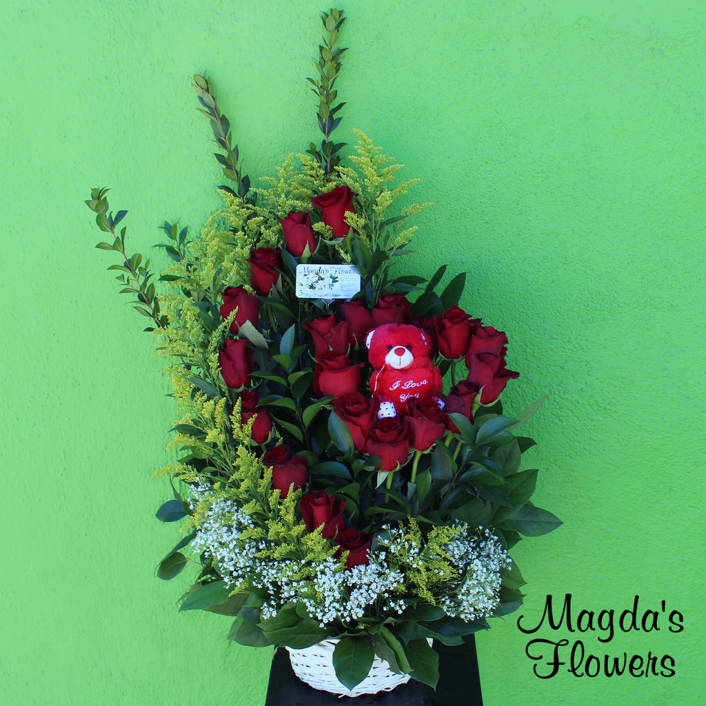 Charming Heart - This floral basket is the perfect way to show your affection with a charming gesture. It features an adorable heart shape arrangement of red roses as the centerpiece, adorned by a thin cresent moon of red roses and lush greenery.  A small teddy bear is included to add a touch of sweetness to this special gift.